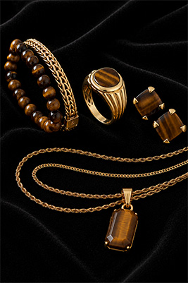 Coordinated Tiger's Eye men's jewelry collection with matching gold tones, bracelet stack, ring, earrings, and chains.