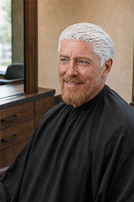 Strong masculine Doug sitting confidently in a salon while his strawberry-blond hair color processes