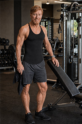 Fit and energetic Doug at 75 standing confidently in a good everyday gym after his workout