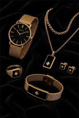 Matched men's jewelry collection arranged on black velvet with gold Tiger Eye pieces including a watch, ring, bracelet, necklace, pendant, and earrings.